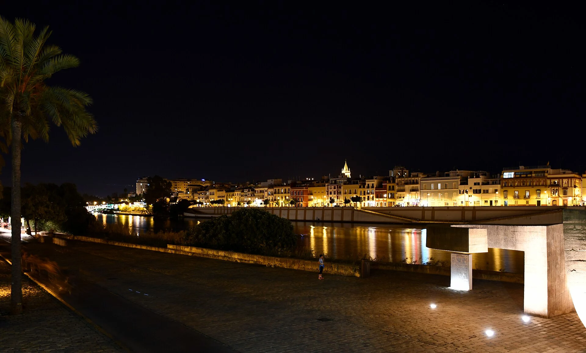 La calle Betis de Sevilla de noche vista desde la otra orilla del Guadalquivir, con las fachadas iluminadas reflejadas en el río