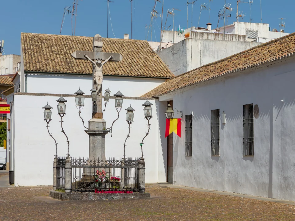 Plaza de Capuchinos de Córdoba con el Cristo de los Faroles, faroles de hierro y casas encaladas a pleno día