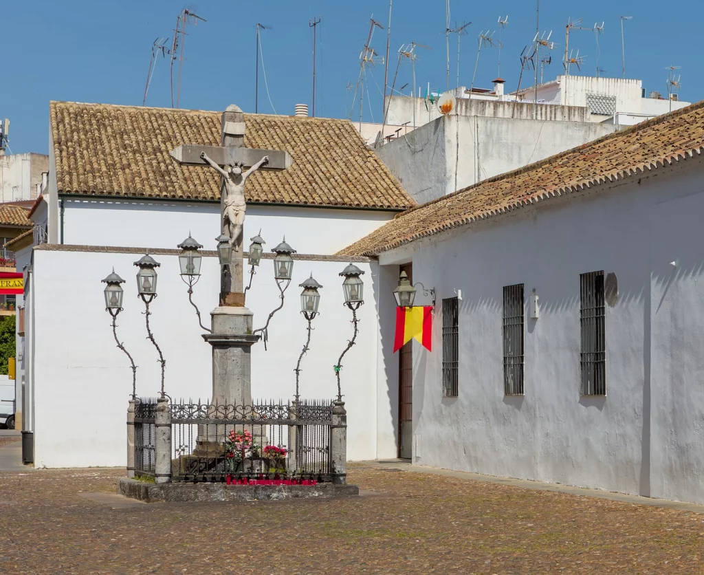 Plaza de Capuchinos de Córdoba con el Cristo de los Faroles rodeado de faroles de hierro, muros encalados y suelo empedrado