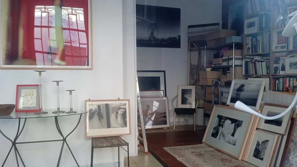 Estudio de Vari Caramés en A Coruña, con copias en color y en blanco y negro enmarcadas, unas colgadas y otras apoyadas en el suelo junto a una librería